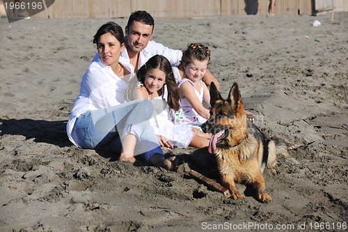 Image of happy family playing with dog on beach