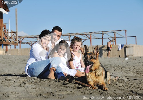 Image of happy family playing with dog on beach