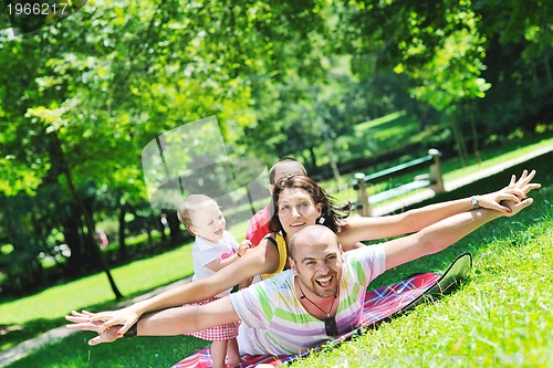 Image of happy young couple with their children have fun at park