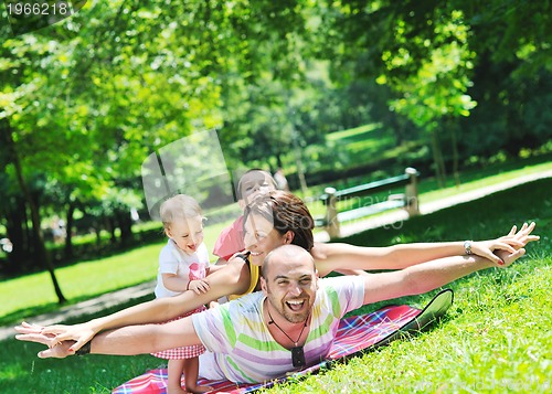 Image of happy young couple with their children have fun at park