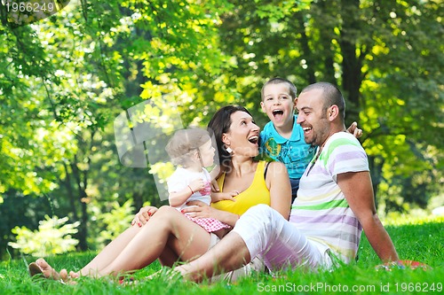 Image of happy young couple with their children have fun at park