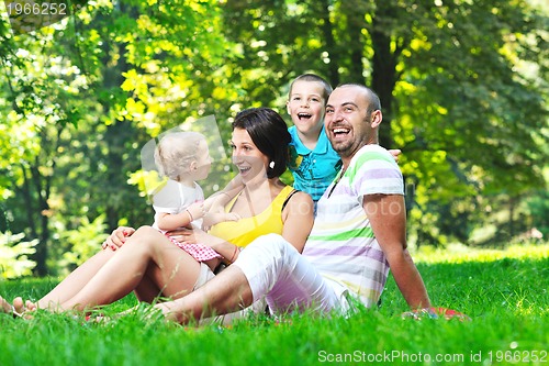 Image of happy young couple with their children have fun at park