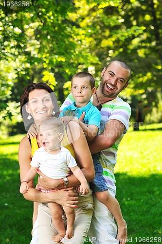 Image of happy young couple with their children have fun at park