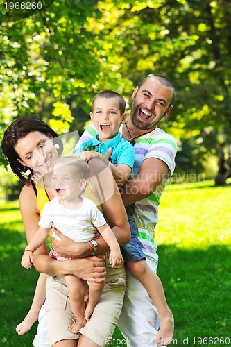 Image of happy young couple with their children have fun at park