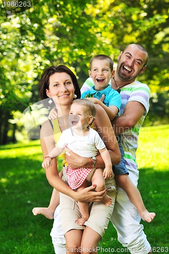 Image of happy young couple with their children have fun at park