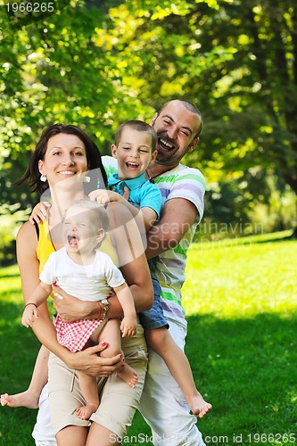 Image of happy young couple with their children have fun at park