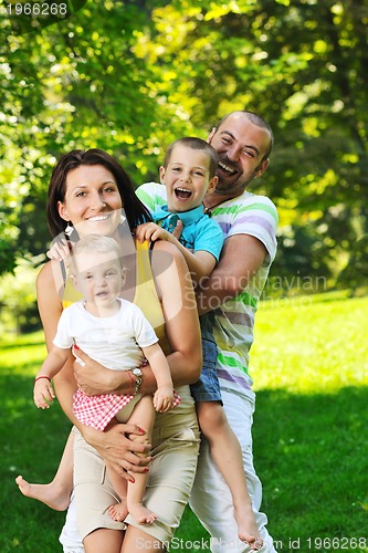 Image of happy young couple with their children have fun at park