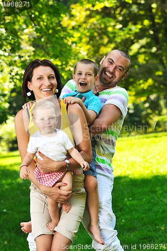 Image of happy young couple with their children have fun at park