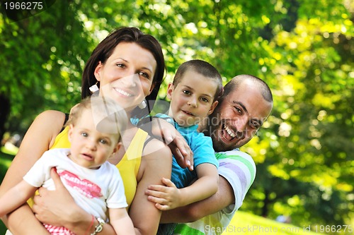 Image of happy young couple with their children have fun at park