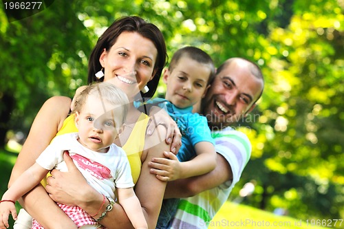 Image of happy young couple with their children have fun at park