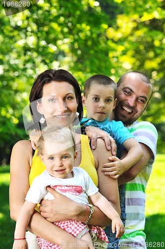 Image of happy young couple with their children have fun at park
