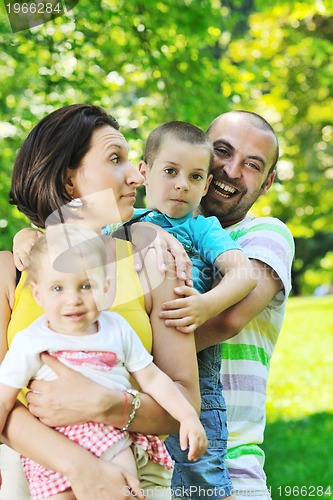 Image of happy young couple with their children have fun at park