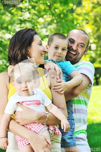 Image of happy young couple with their children have fun at park