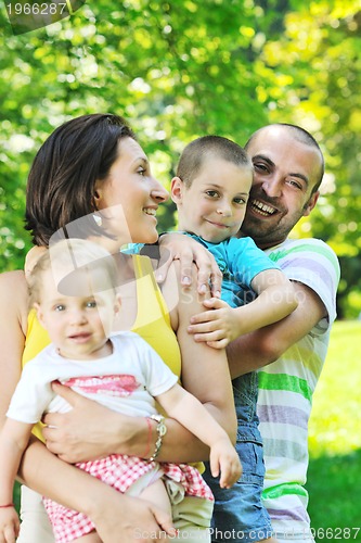 Image of happy young couple with their children have fun at park