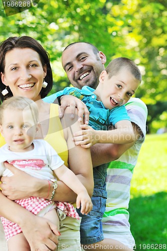 Image of happy young couple with their children have fun at park
