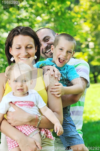Image of happy young couple with their children have fun at park