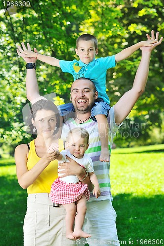 Image of happy young couple with their children have fun at park