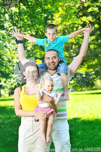 Image of happy young couple with their children have fun at park
