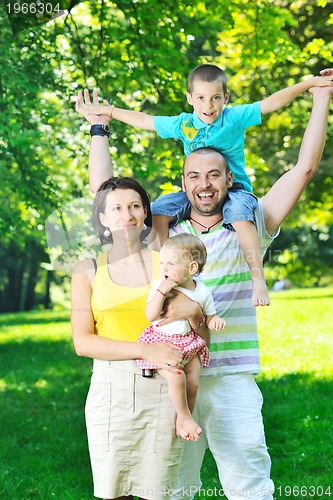 Image of happy young couple with their children have fun at park