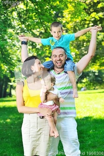 Image of happy young couple with their children have fun at park