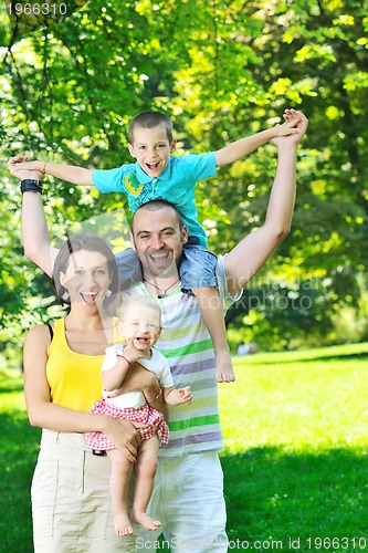 Image of happy young couple with their children have fun at park