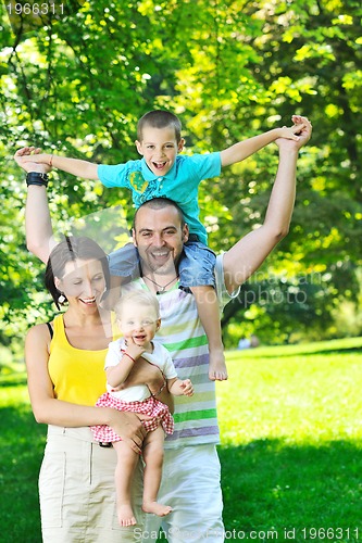 Image of happy young couple with their children have fun at park