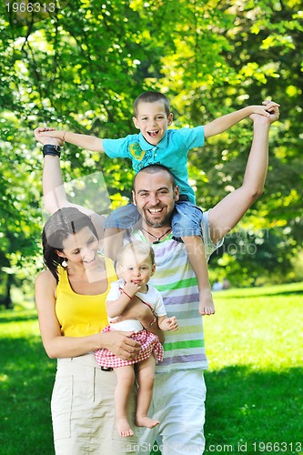 Image of happy young couple with their children have fun at park