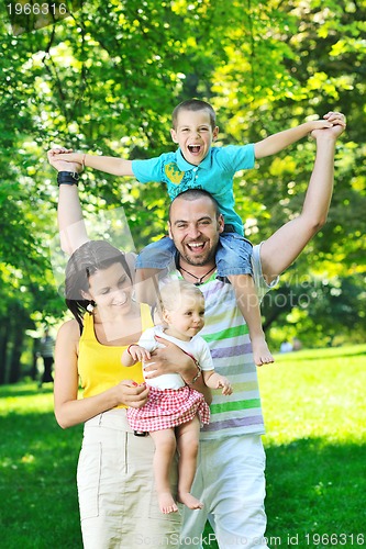 Image of happy young couple with their children have fun at park