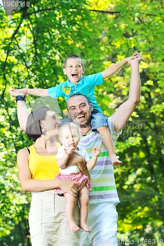 Image of happy young couple with their children have fun at park