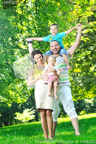 Image of happy young couple with their children have fun at park