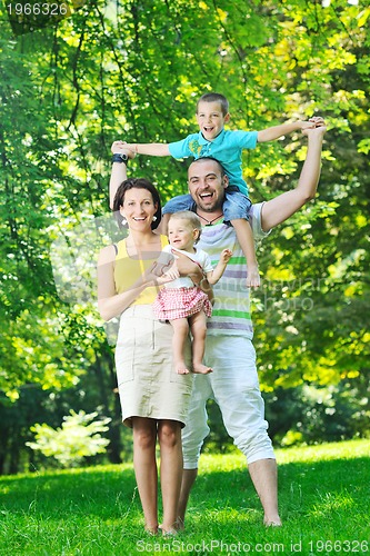 Image of happy young couple with their children have fun at park