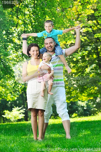 Image of happy young couple with their children have fun at park