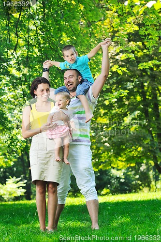 Image of happy young couple with their children have fun at park