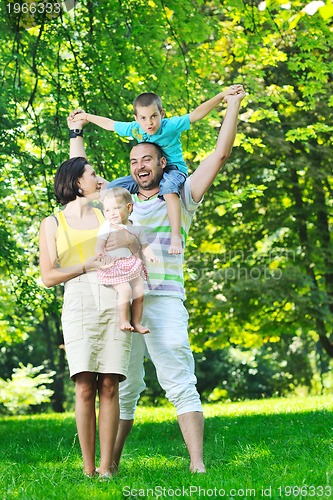 Image of happy young couple with their children have fun at park
