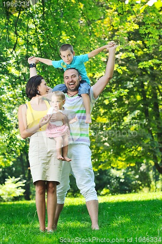 Image of happy young couple with their children have fun at park