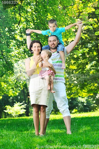 Image of happy young couple with their children have fun at park