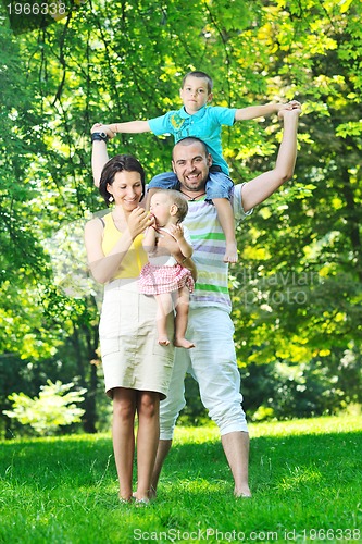 Image of happy young couple with their children have fun at park