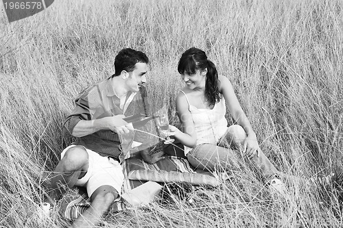 Image of happy couple enjoying countryside picnic in long grass