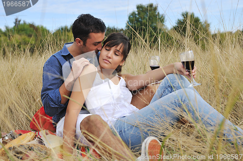 Image of happy couple enjoying countryside picnic in long grass