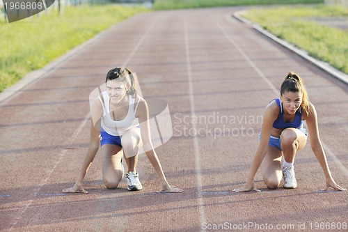 Image of two girls running on athletic race track