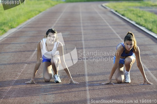 Image of two girls running on athletic race track