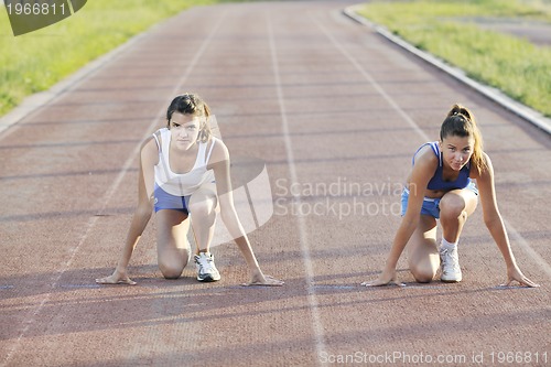 Image of two girls running on athletic race track