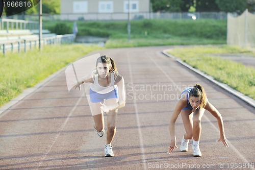 Image of two girls running on athletic race track