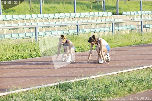 Image of two girls running on athletic race track