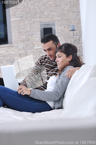 Image of joyful couple relax and work on laptop computer at modern home