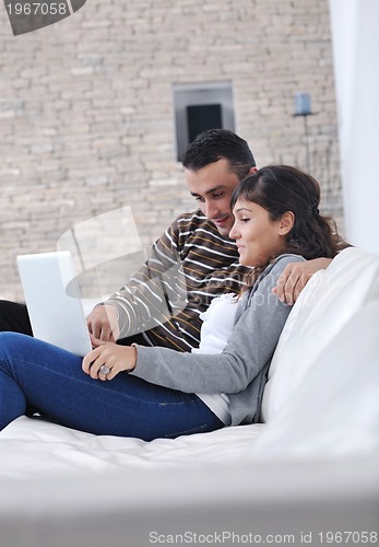 Image of joyful couple relax and work on laptop computer at modern home