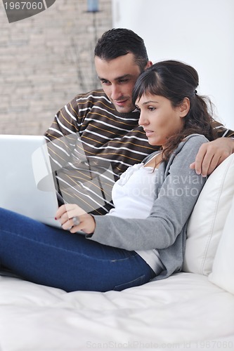 Image of joyful couple relax and work on laptop computer at modern home