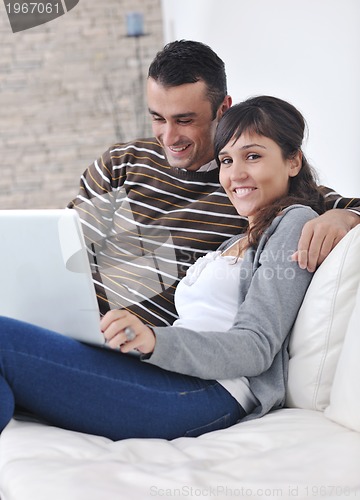 Image of joyful couple relax and work on laptop computer at modern home