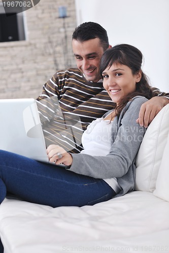 Image of joyful couple relax and work on laptop computer at modern home