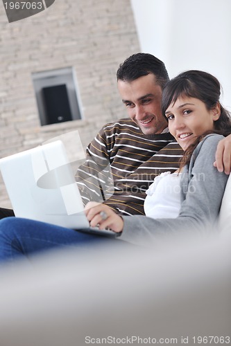 Image of joyful couple relax and work on laptop computer at modern home